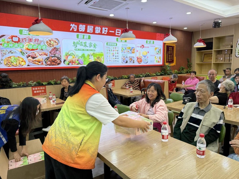 圖：社區(qū)工作者為居民派發(fā)活動紀念品.jpg